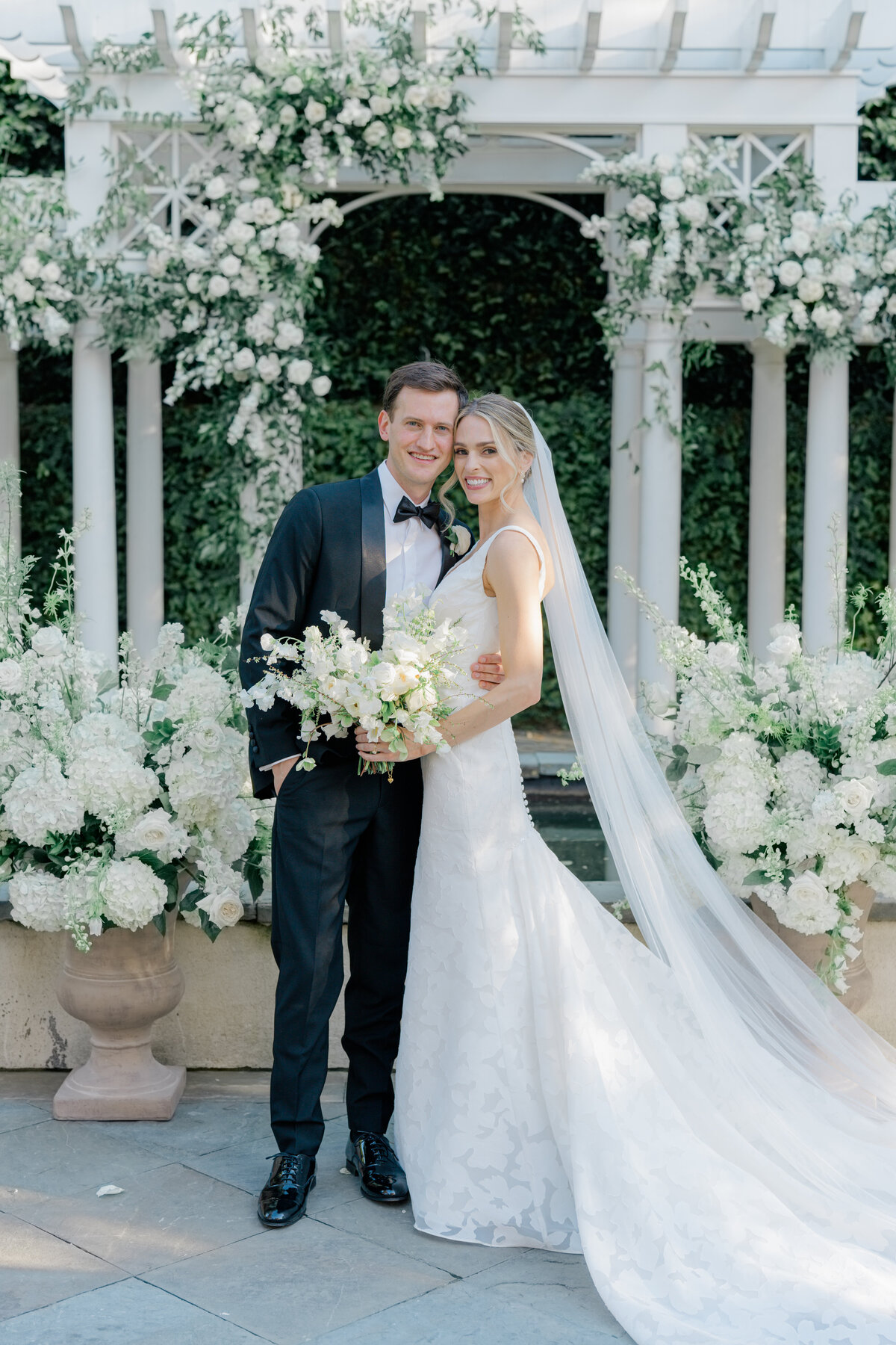 William Aiken House spring wedding. Bride and groom pause for a picture in front of their wedding ceremony flowers. Spring wedding in downtown Charleston. Kailee DiMeglio Photography.,