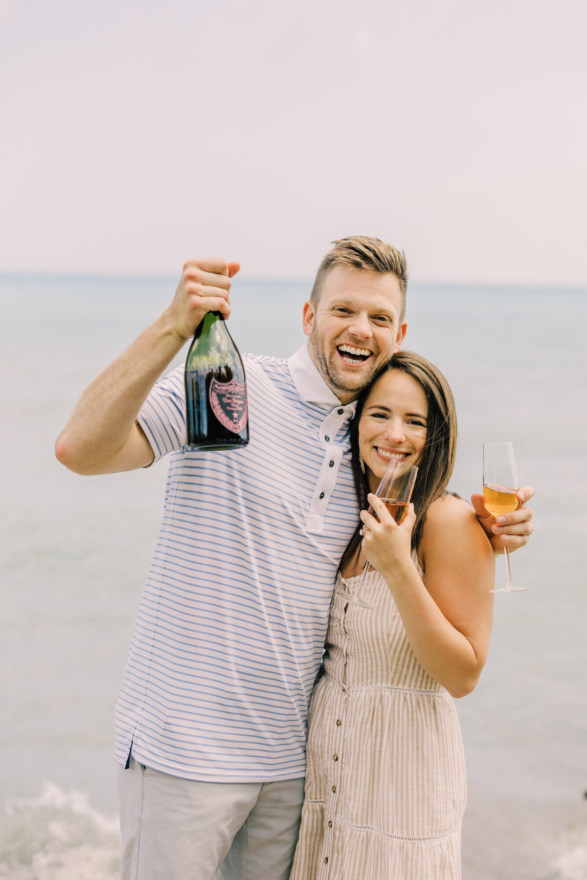 A couple pop open a bottle of Dom Perignon in front of beautiful Lake Michigan