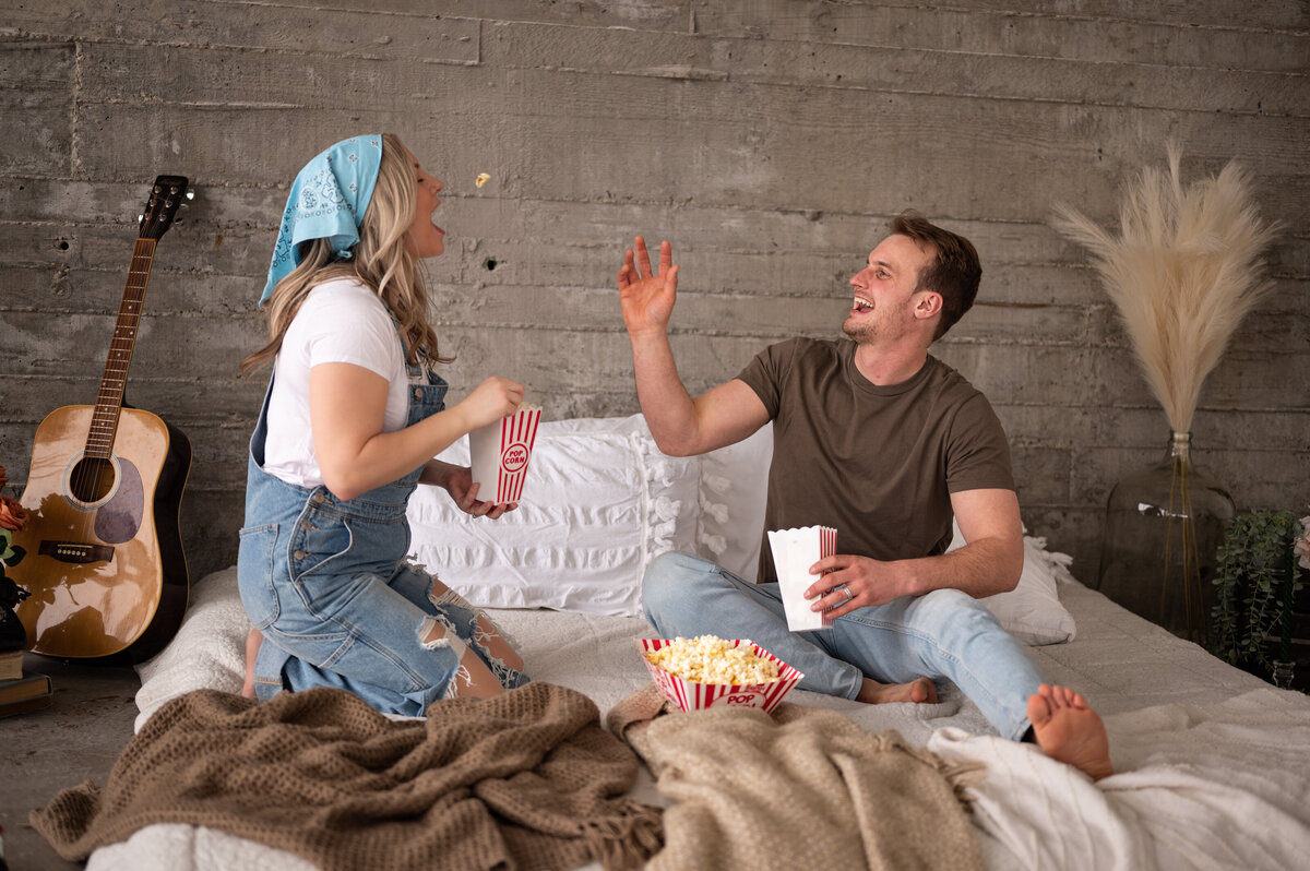couple throwing popcorn for each other during fun and candid engagement session