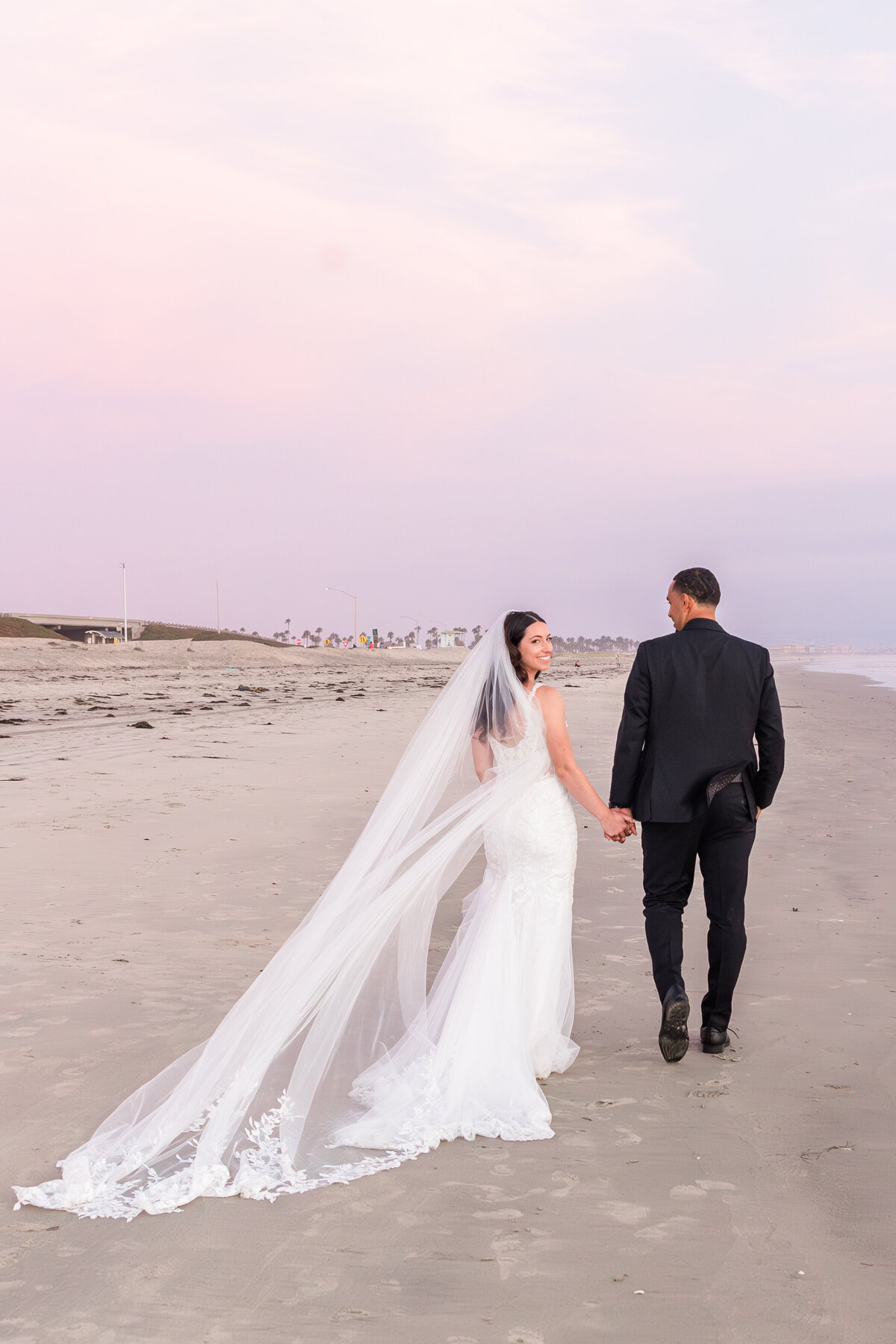 bride and groom walking down Coronado beach at sunset