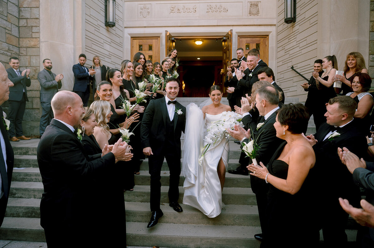 bride and groom walk down stairs outside of their ceremony and everyone cheers photo by cait fletcher photography