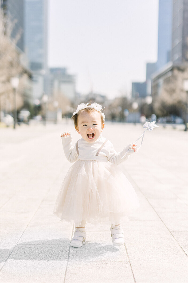 花冠をかぶって星のステッキを手に持って、満面の笑みで歩いている可愛らしい1歳の女の子のバースデーフォト