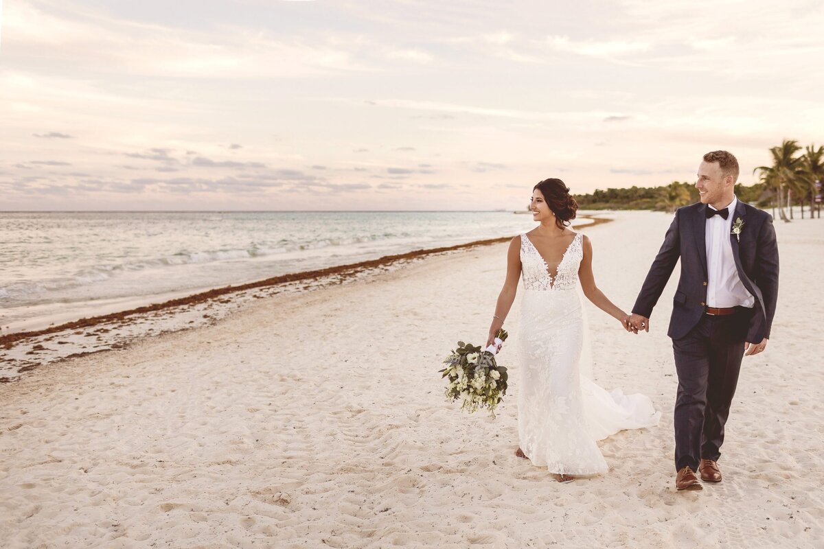 Bride and groom walking down beach at Secrets Maroma Riviera Maya