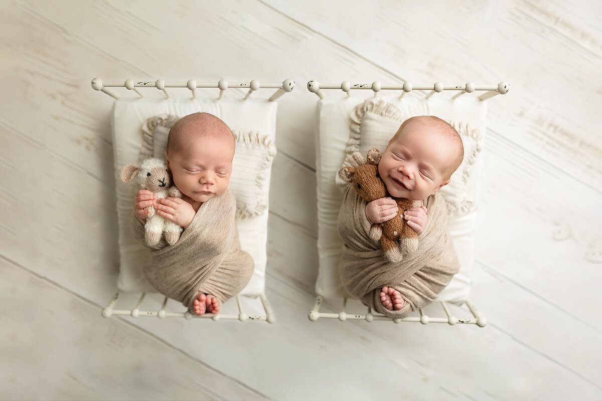 Twin baby boys wrapped and sleeping on newborn beds during their newborn session.