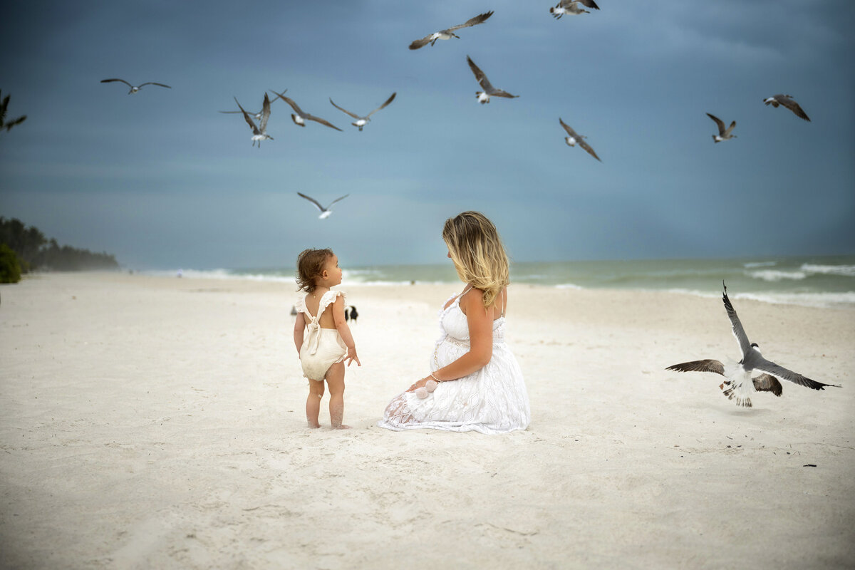 Mother and daughter during maternity photoshoot at Naples white sand beach looking at seagulls