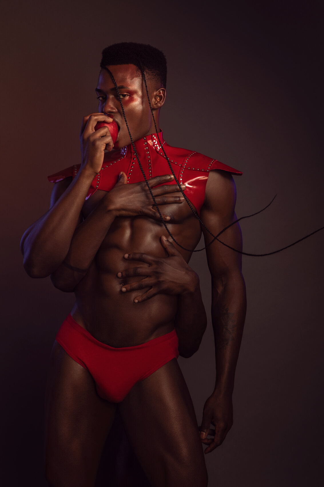 Bold portrait of Jonzu Julian in red, highlighting his physique and strength, captured by Ylva Erevall.