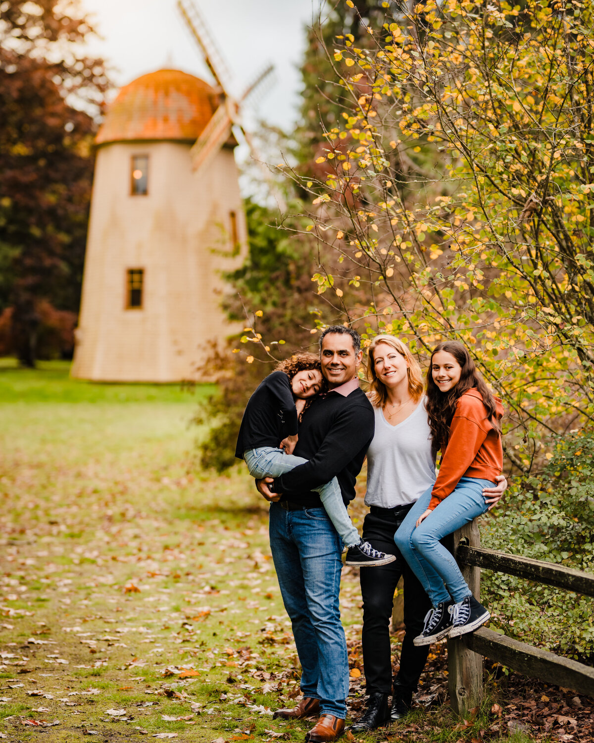 Autumn family portraits taken in Redmond WA by a picturesque windmill amidst the yellow leaves and fall colors.