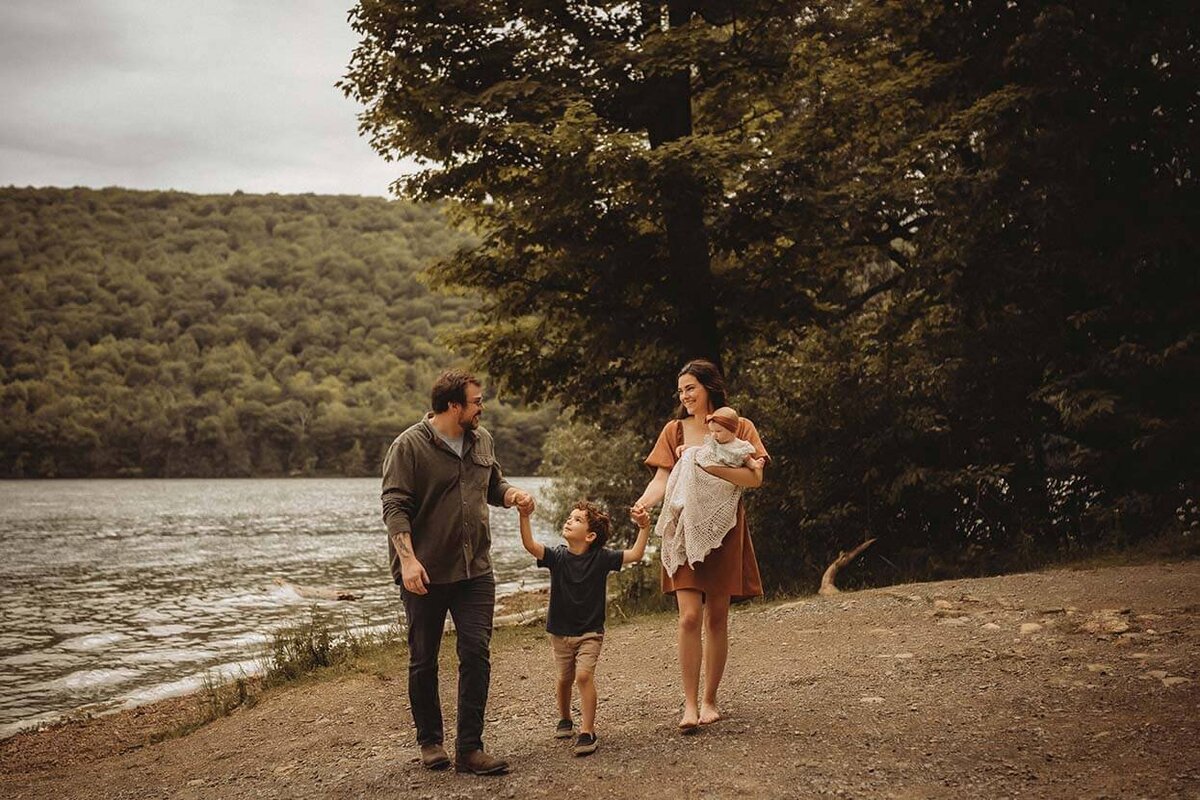 A family of four all looking at each other while holding hands and walking towards the camera in Rochester, NY
