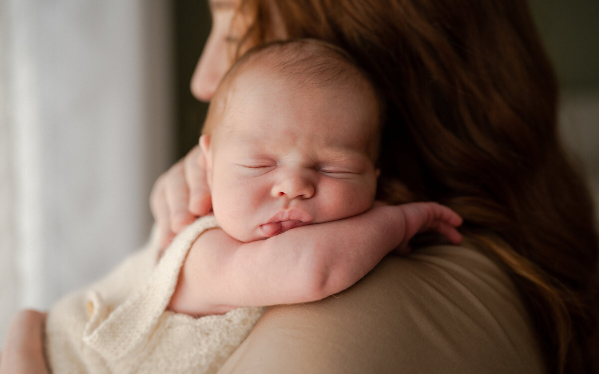 Newborn baby girl asleep on her moms shoulder