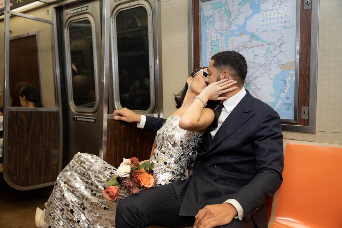 Bride sitting on iconic orange subway seats, holding a colorful bouquet during a modern NYC elopement.