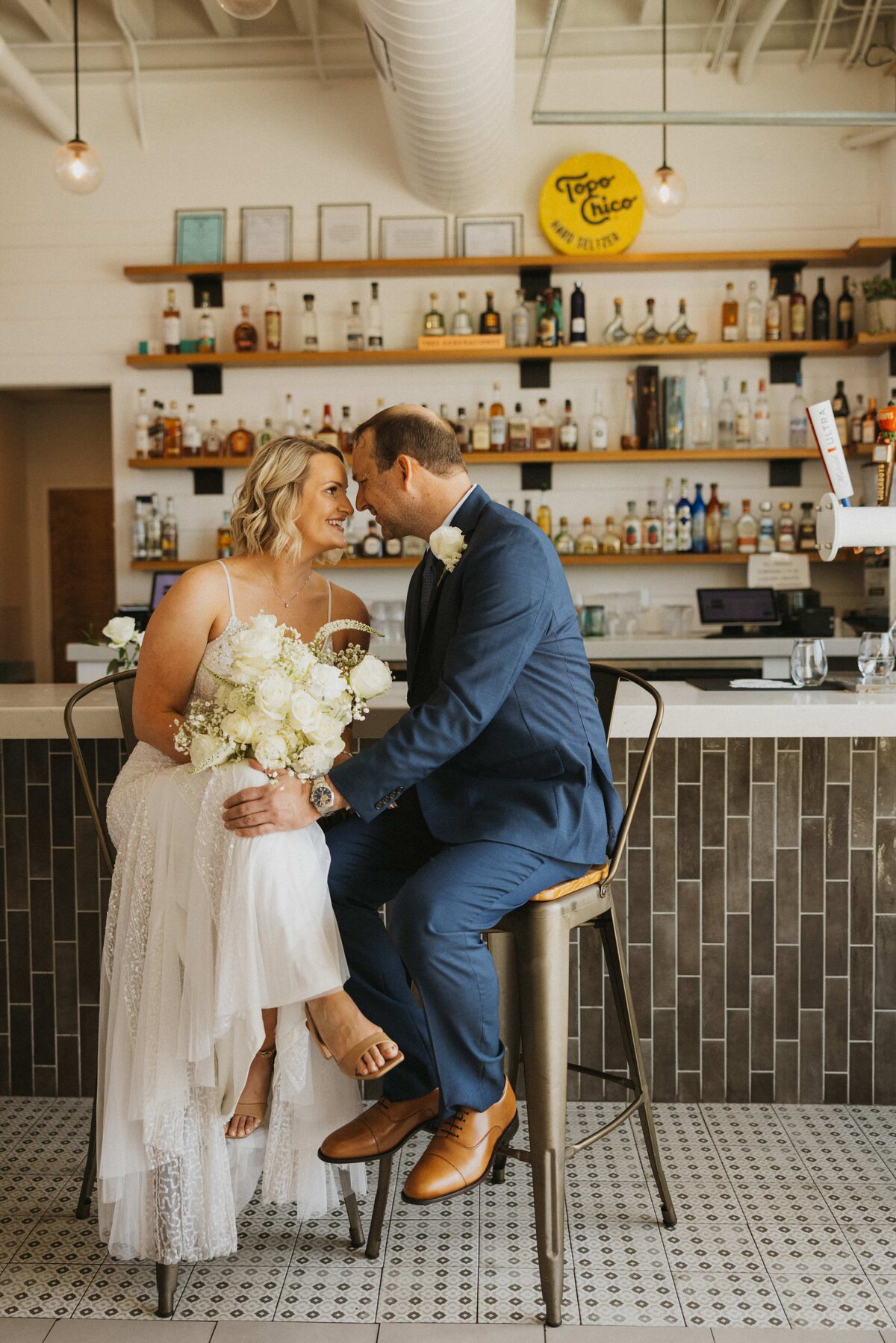 bride and groom sit on bar stools