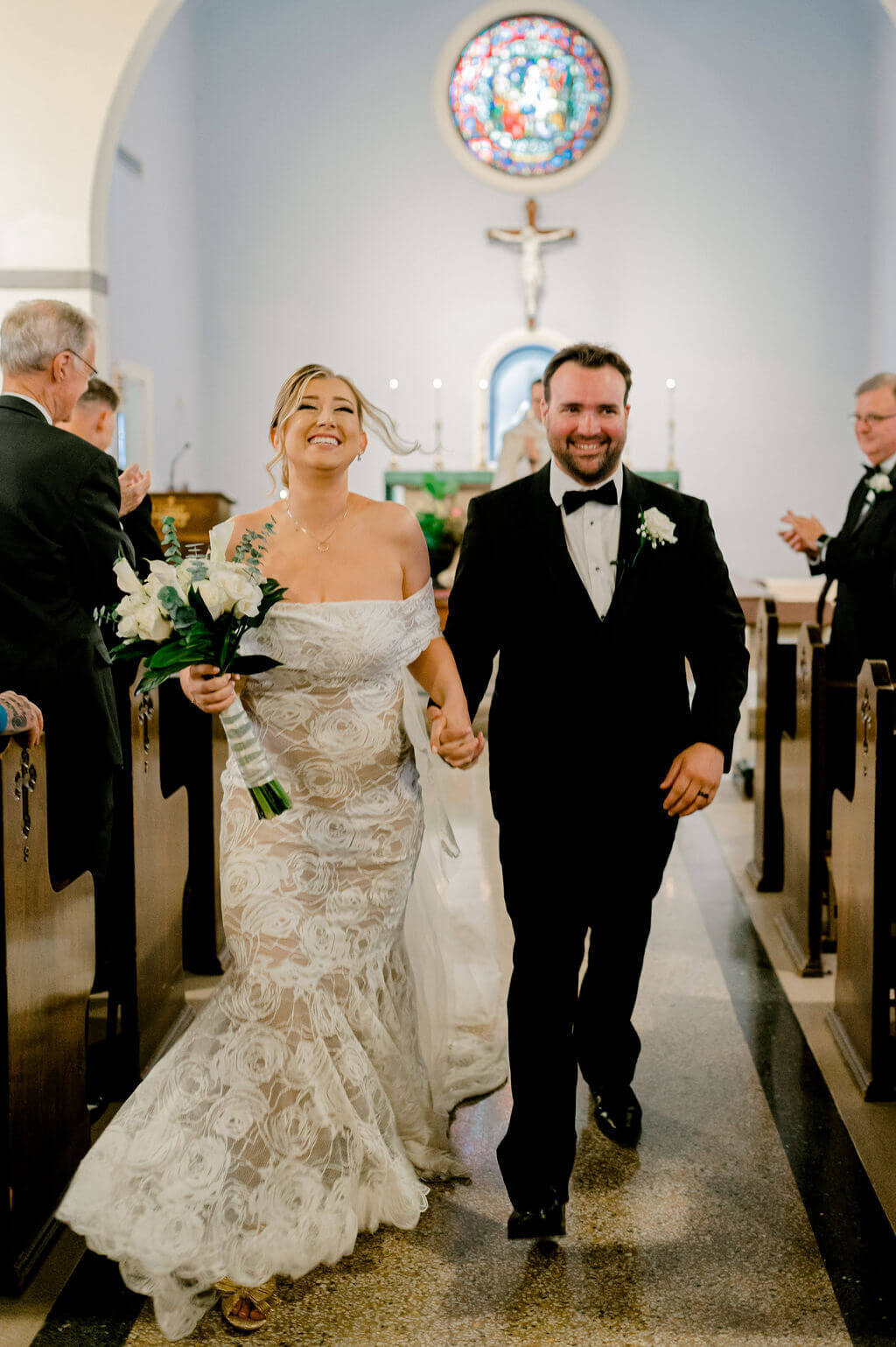 Bride and groom happily recessing up the aisle after being just married in a Catholic church in Georgetown