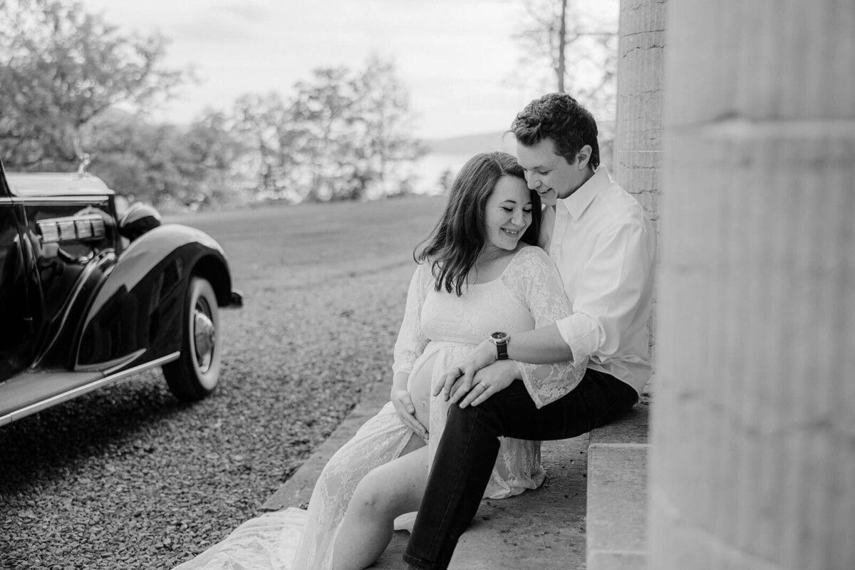 Couple sitting on steps outside historical building at Finger Lakes maternity session, NY