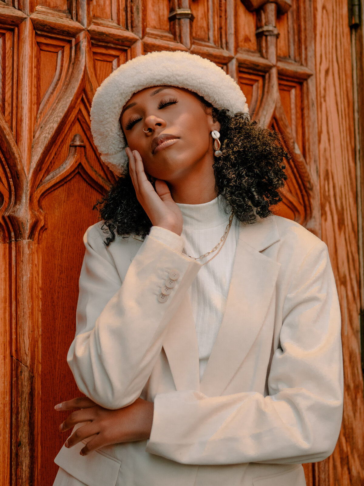 Woman in white hat and blouse in front of ornate wooden doors – vintage-inspired portrait by Mewphotovideo