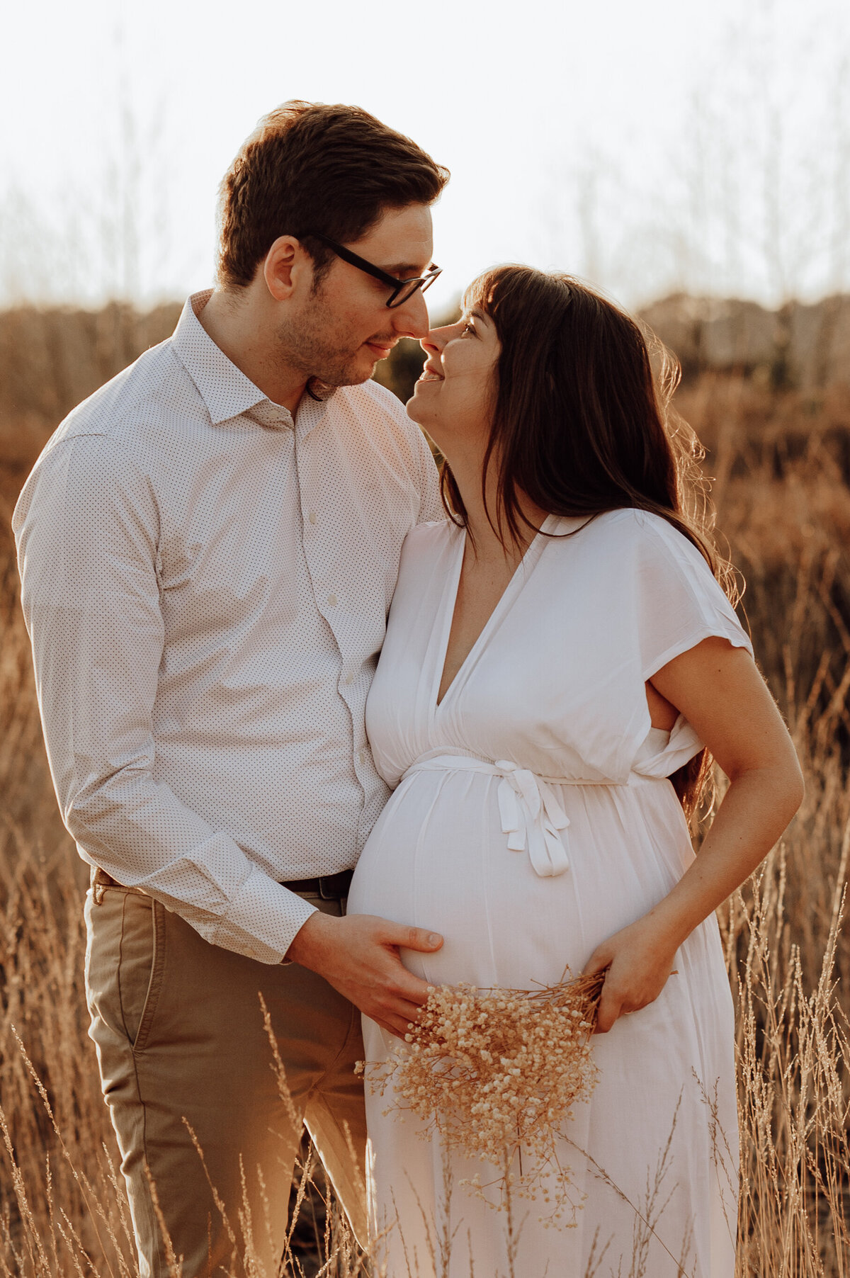 Koppel omhelst elkaar tijdens zwangerschapsshoot in veld