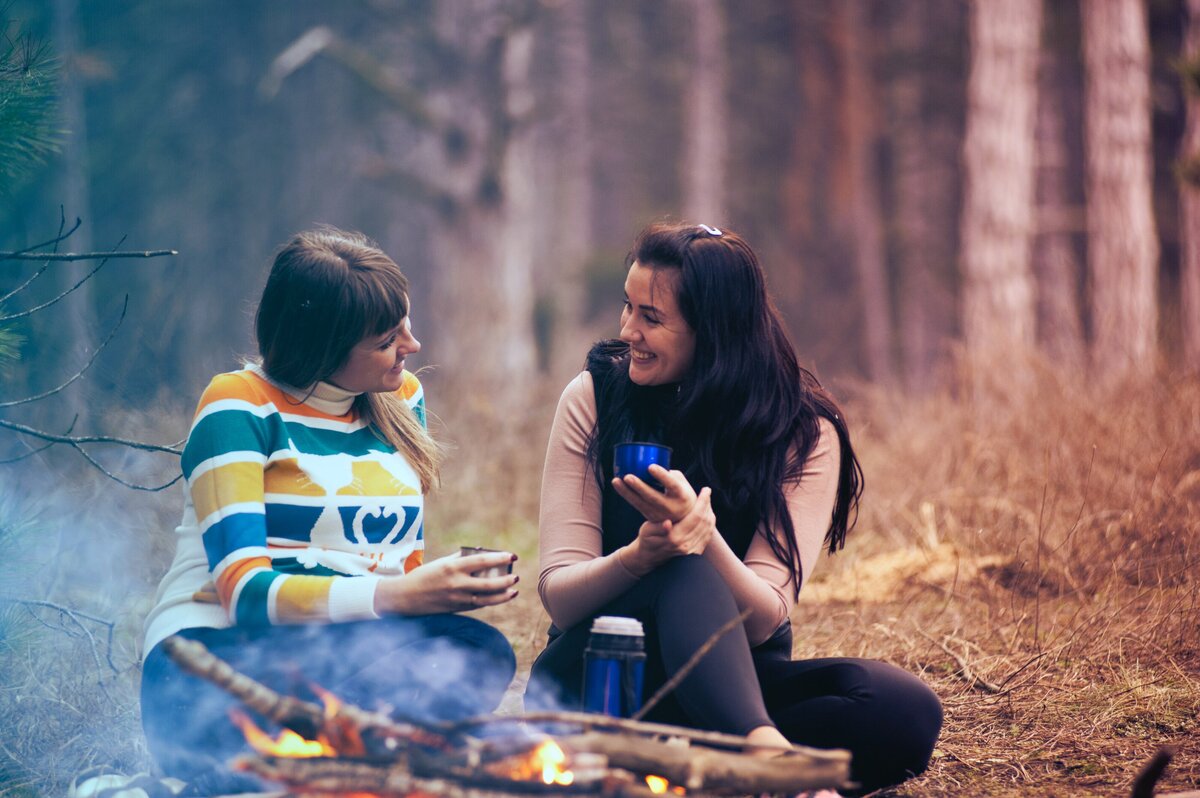 two friends connecting around a campfire