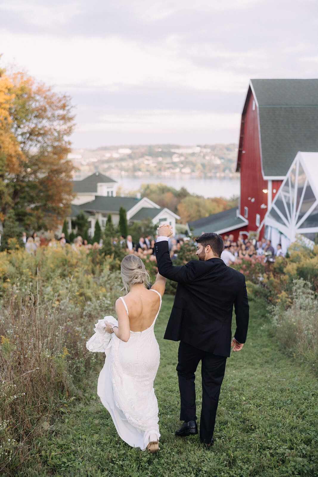 Bride and groom walking along with arms in the air at Finger Lakes Wedding