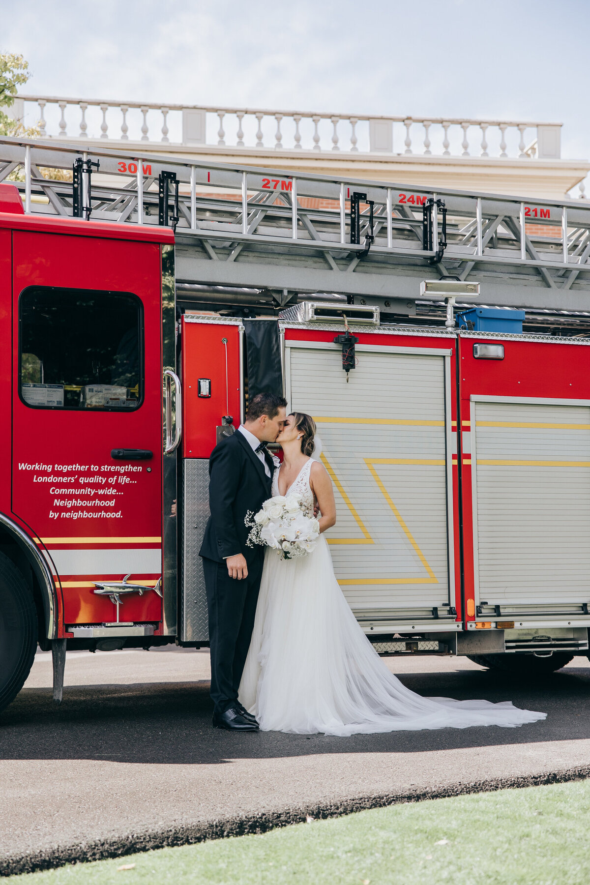 Bride and groom kissing in front of a red fire truck