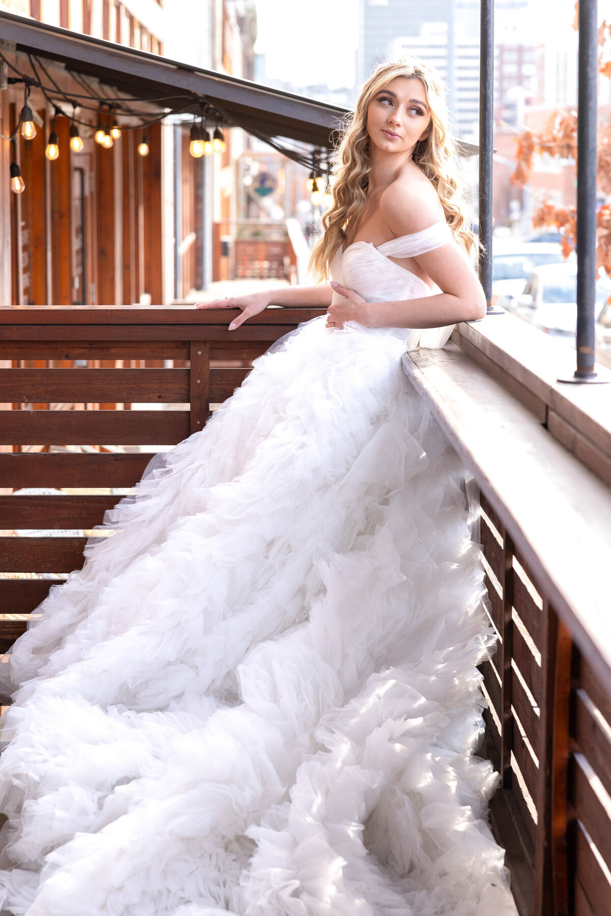 bride leaning on railing looking out at street with backlighting