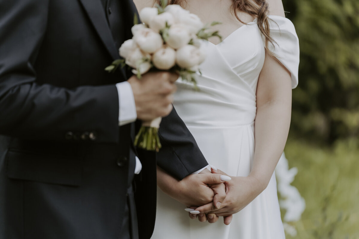 the couple hold hands while the groom's other hand hold the bouquet