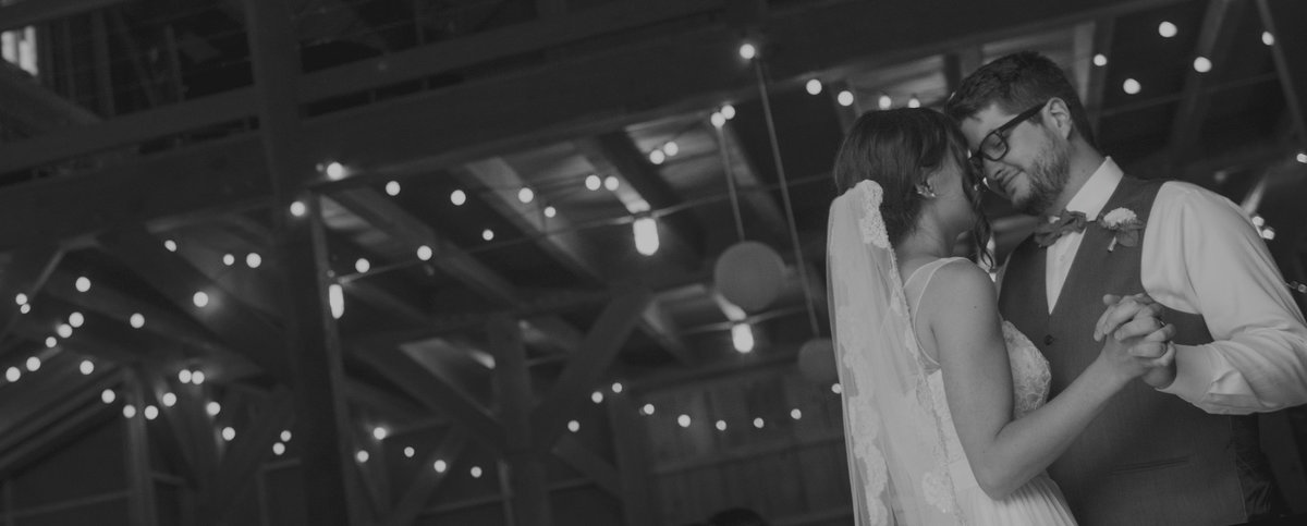 Bride and grooms first dance in a barn lit with twinkle lights