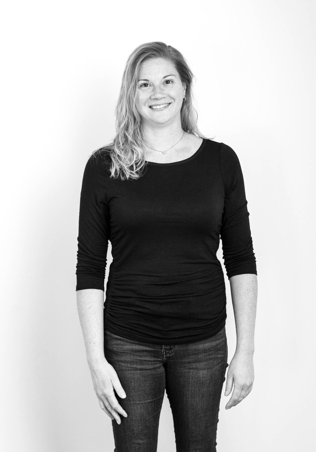 Before shot of a woman with long blonde hair in a black knit cardigan, smiling at the camera.