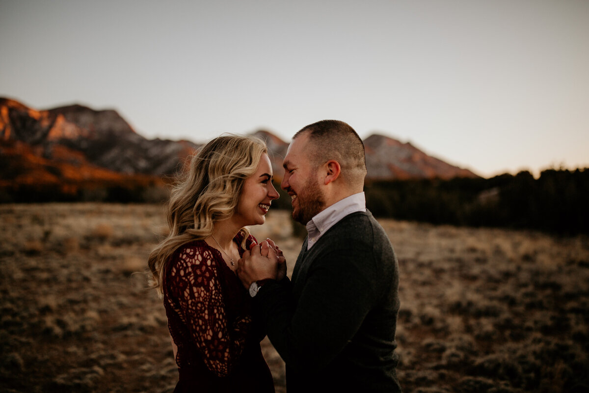 engaged couple holding hands with Sandia mountain behind them