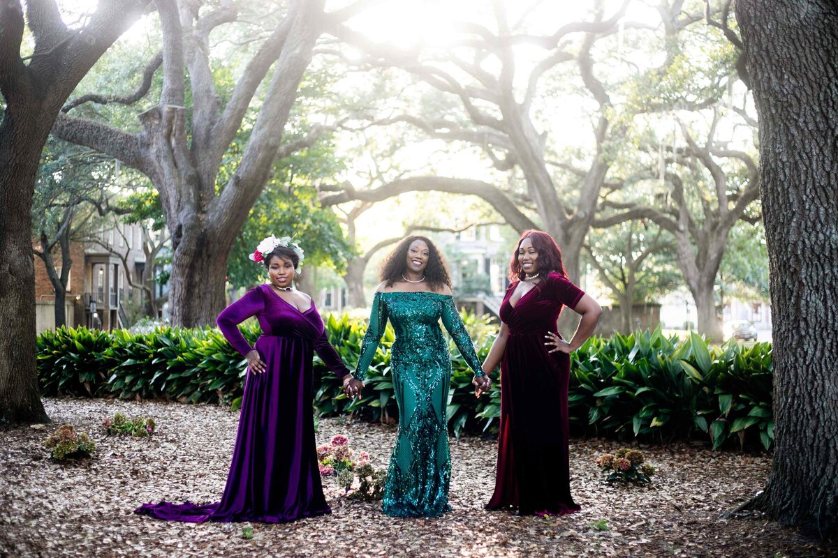 3 women posed in gowns in park