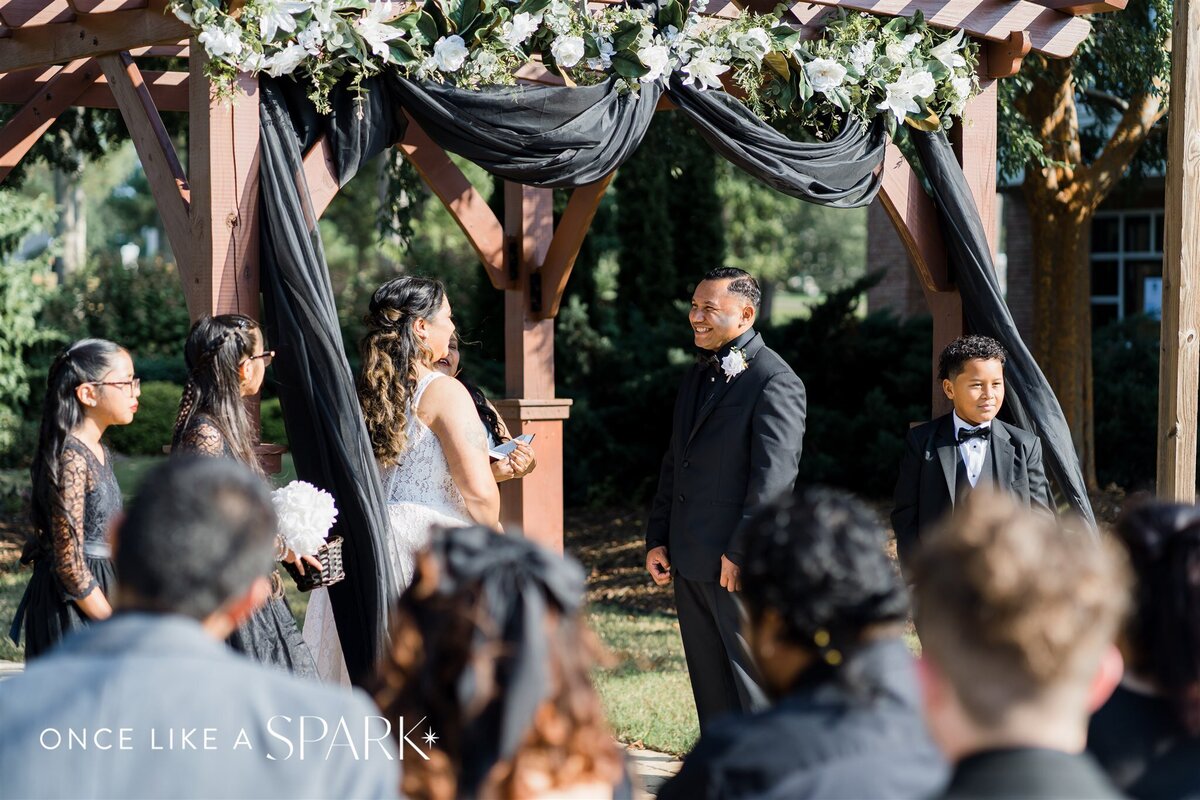 Couple sharing a joyful smile at the altar during their wedding ceremony, surrounded by love and emotion