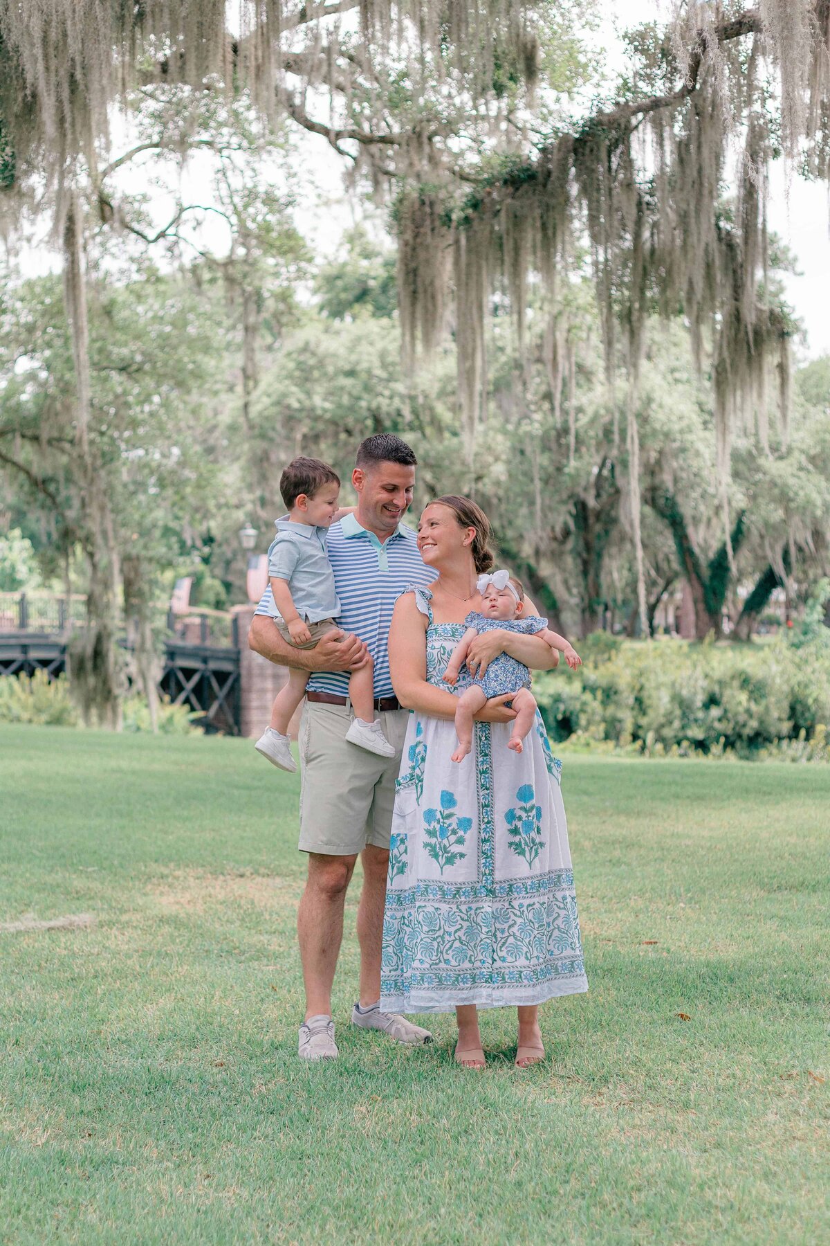 Mom and dad holding their toddler and baby under the majestic oaks of Palmetto Bluff, SC for Hilton Head Photographer, Lamp and Light Photography.