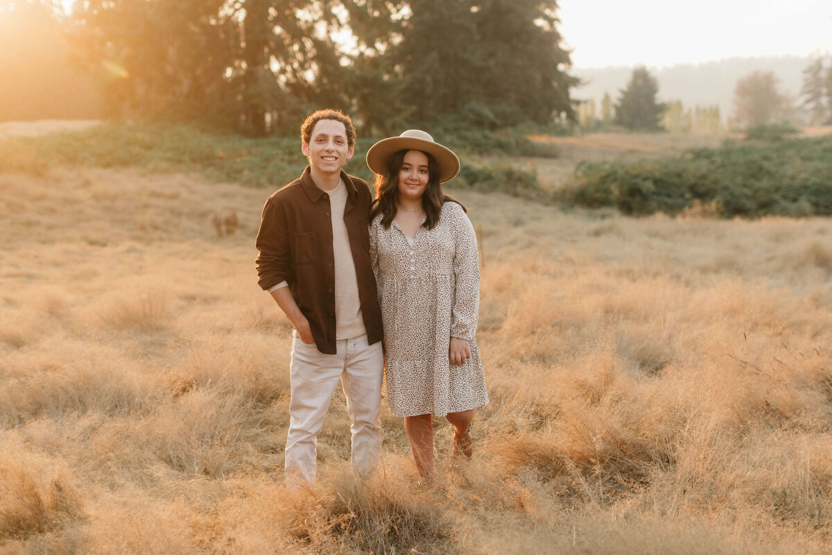 Siblings standing in a field during golden hour