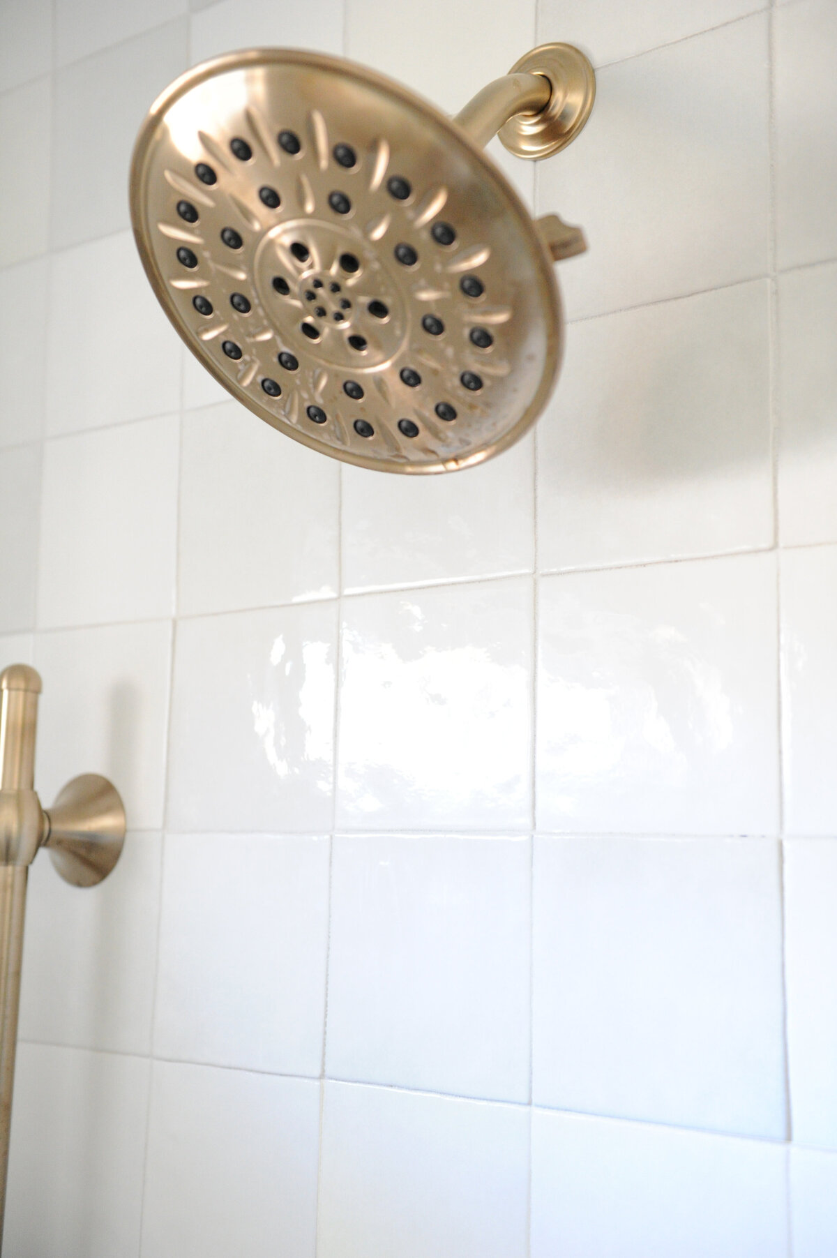Gold shower head mounted to tiled shower wall