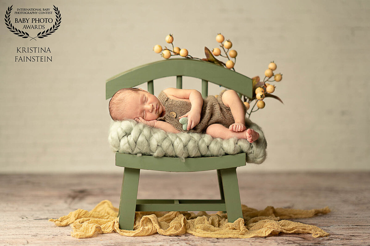 Newborn sleeping on green blanket on mini-chair