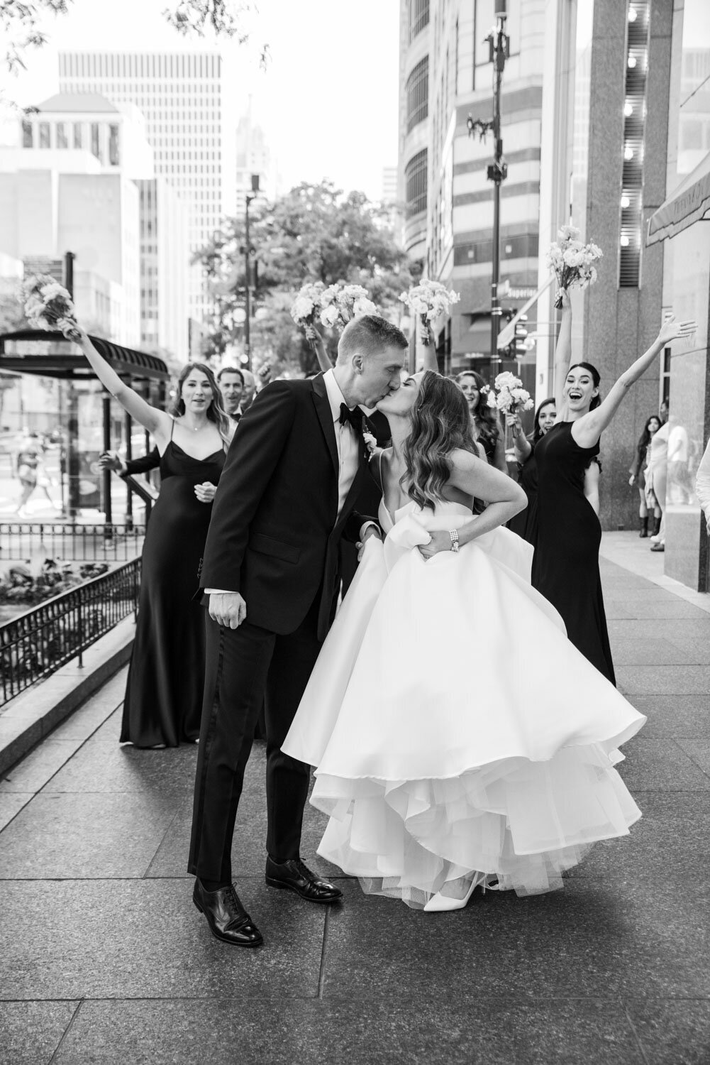 A bride and groom kissing in front of their wedding party