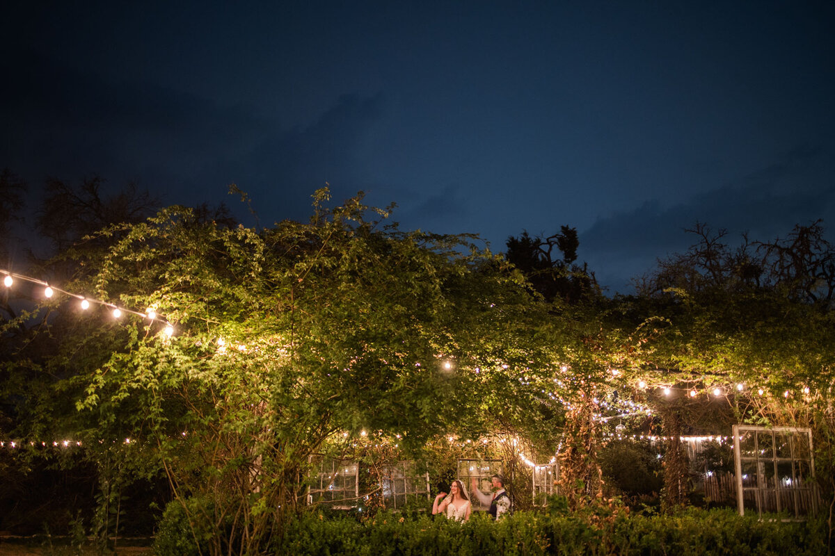 Couple sitting under string lights in a garden at night
