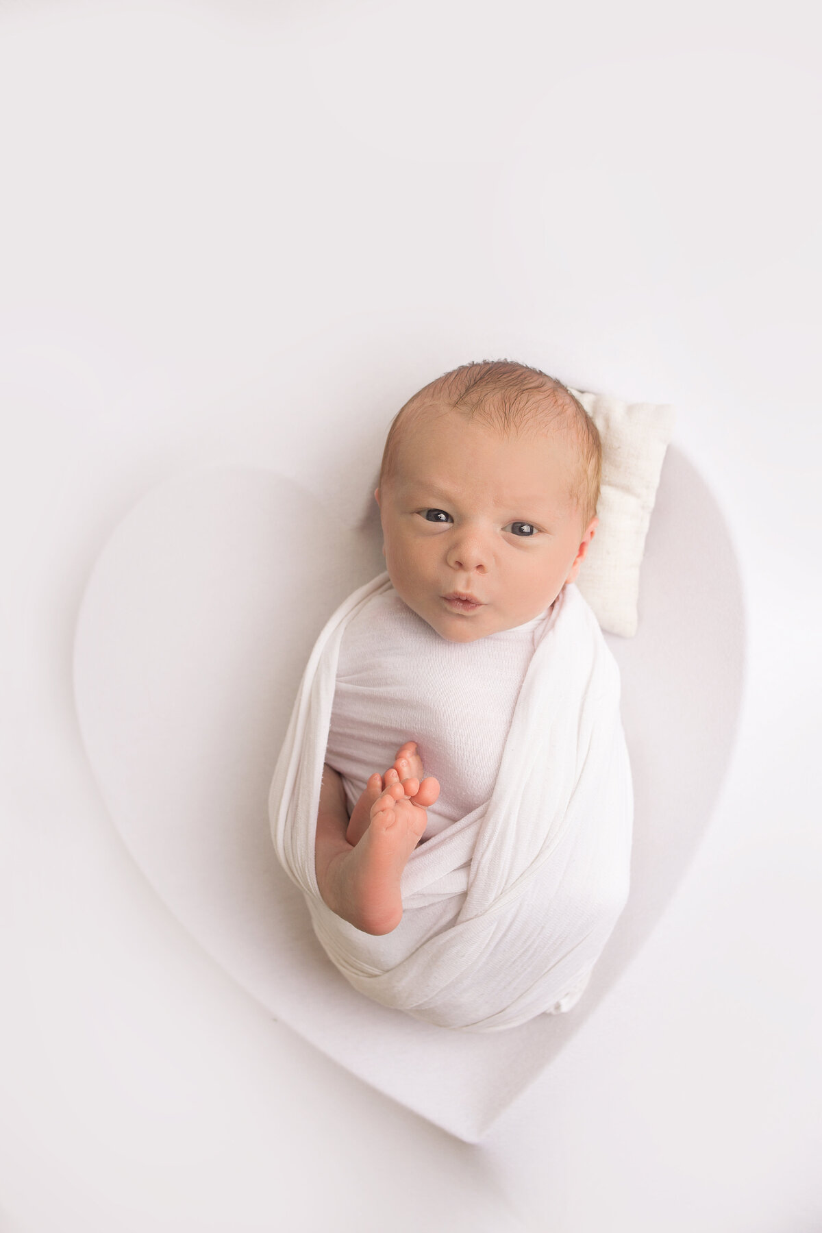 Newborn baby boy wrapped in a white wrap during newborn photoshoot in moutn juliet tennessee photography studio