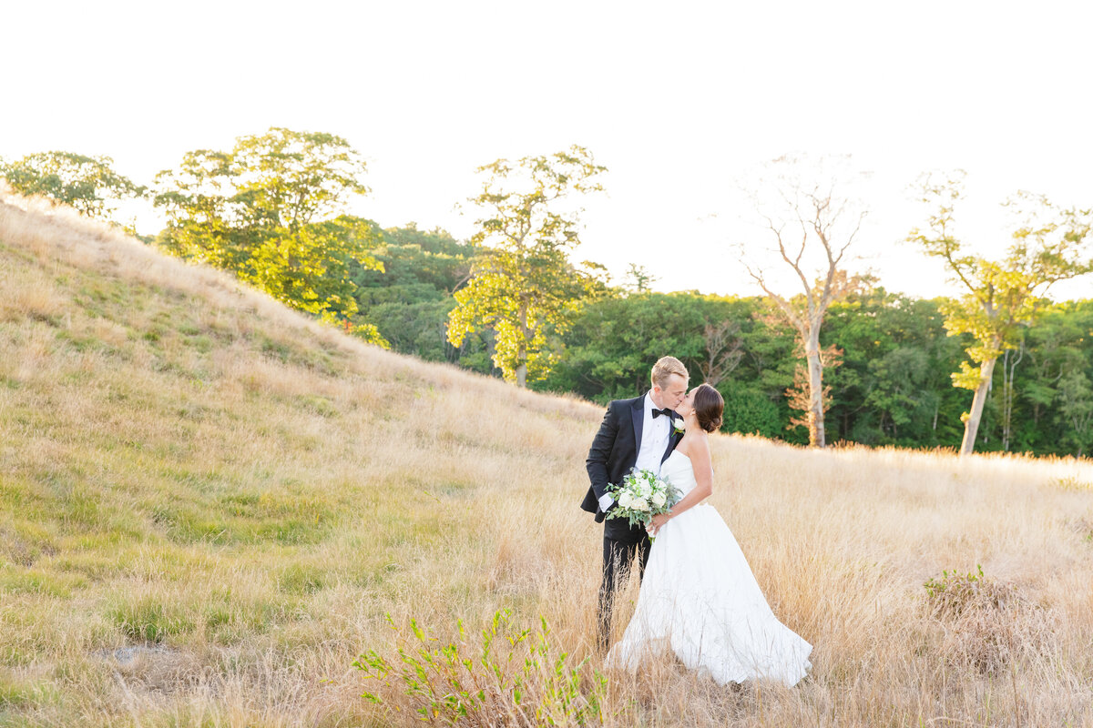 bride and groom kiss in a field