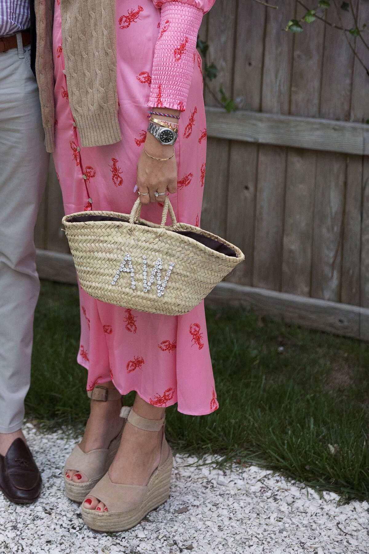 Wedding guest in pink dress holds a rattan purse during Nantucket wedding.