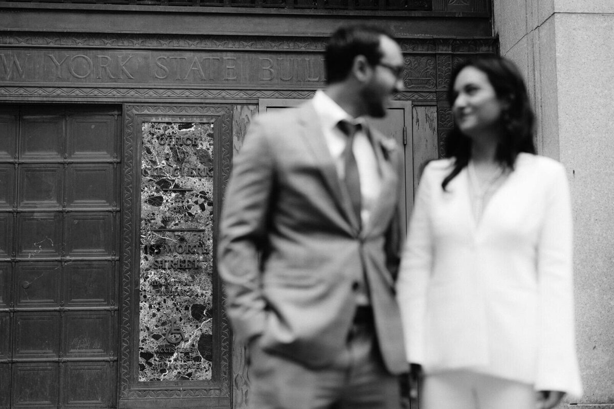 The bride and the groom are happily looking at each other outside the exit door of NY City Hall. Image by Jenny Fu Studio