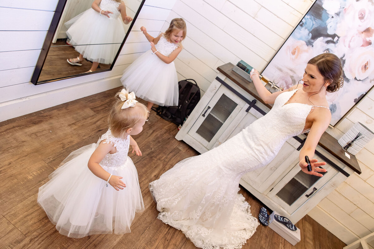 bride dances with two toddler flower girls near mirror at Morgan Creek Barn wedding in Dripping Springs Texas