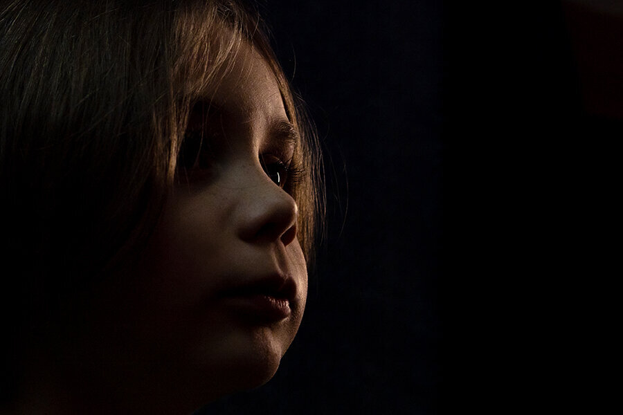 Young child's profile illuminating cheeks and eyes with black background.