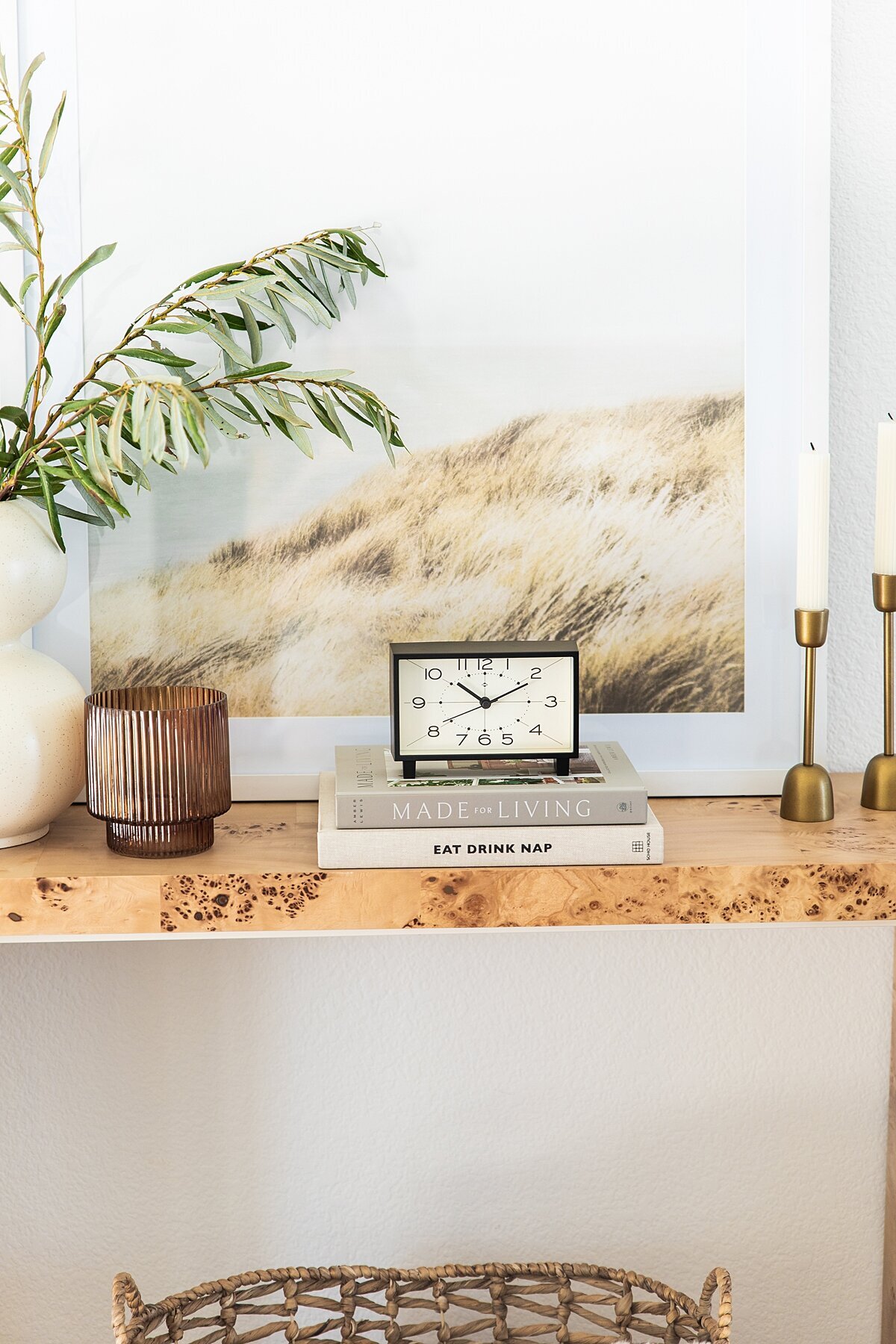 Console table with styled clock, books, and candles in Southern California.