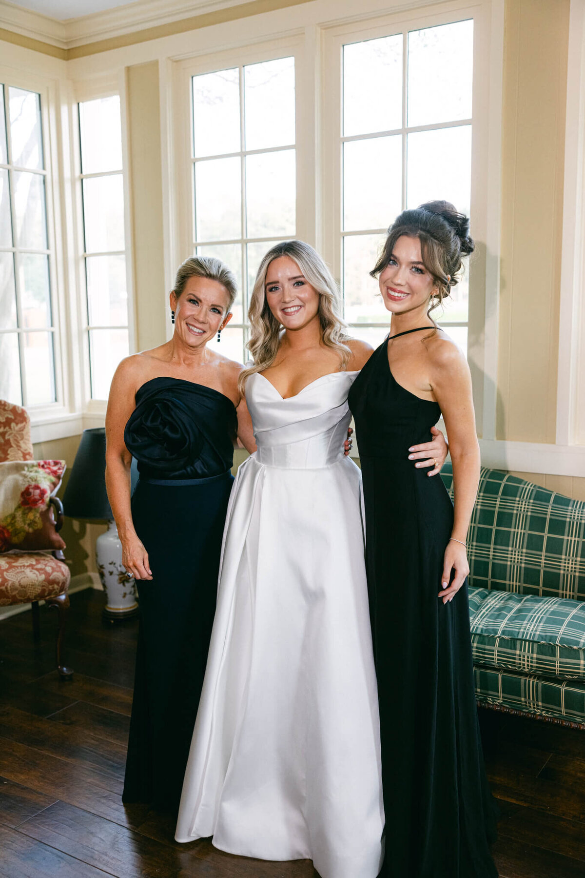 A wedding day photo of the bride her mom and sister posing for a portrait