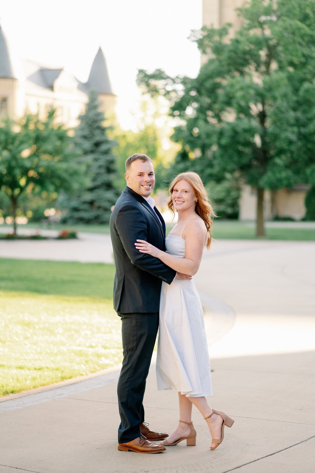 engaged couple smiling while standing on Notre Dame's campus