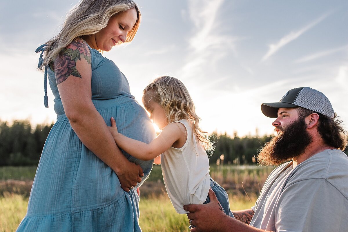 family maternity photos with sibling kissing belly