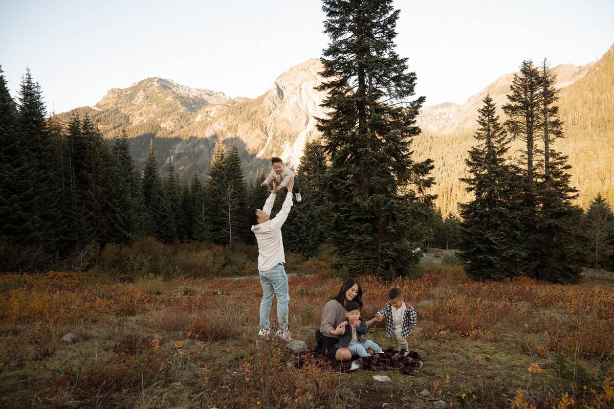 a male and a female with triplet sons outdoors with a mountain backdrop