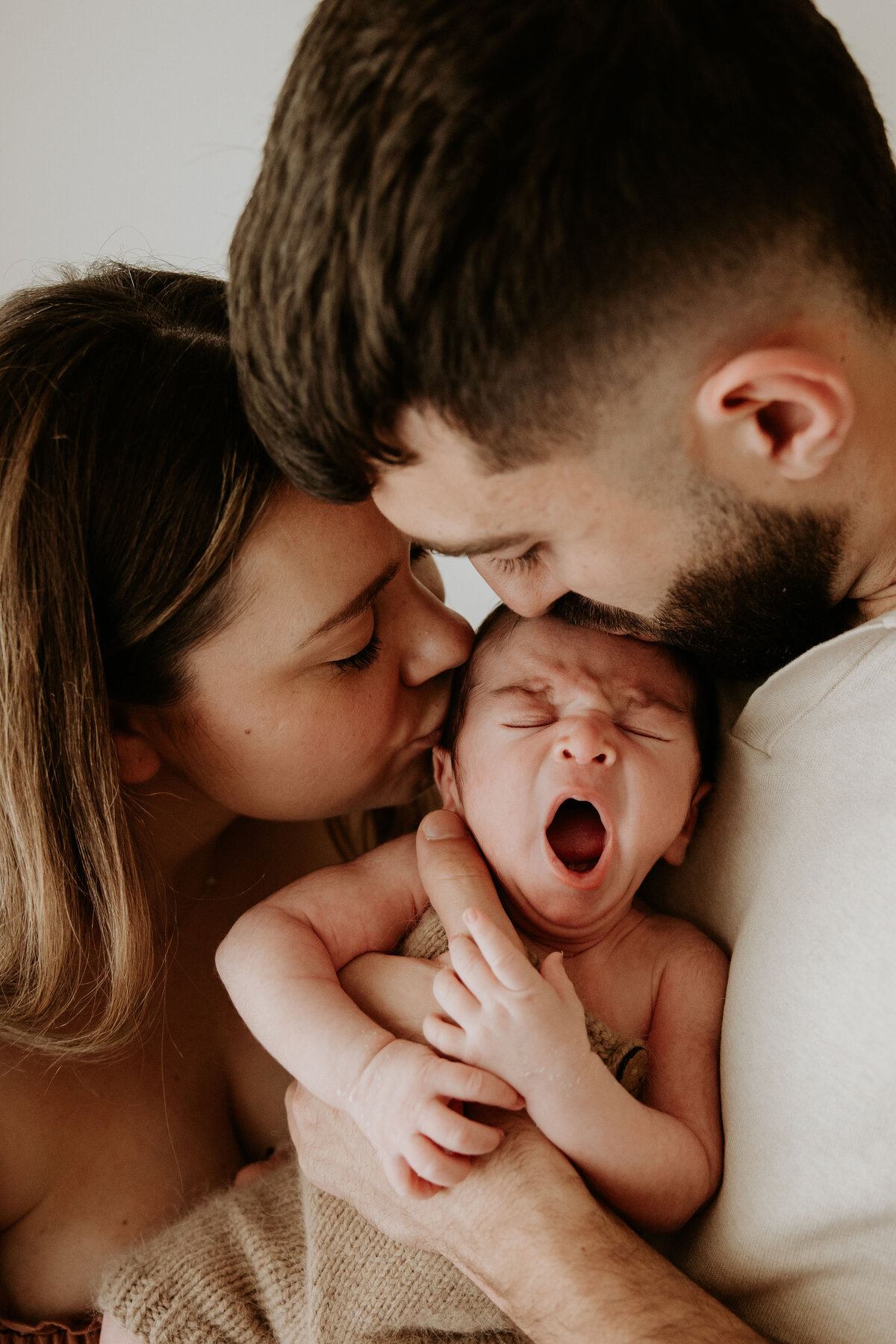 Parents hold yawning newborn baby