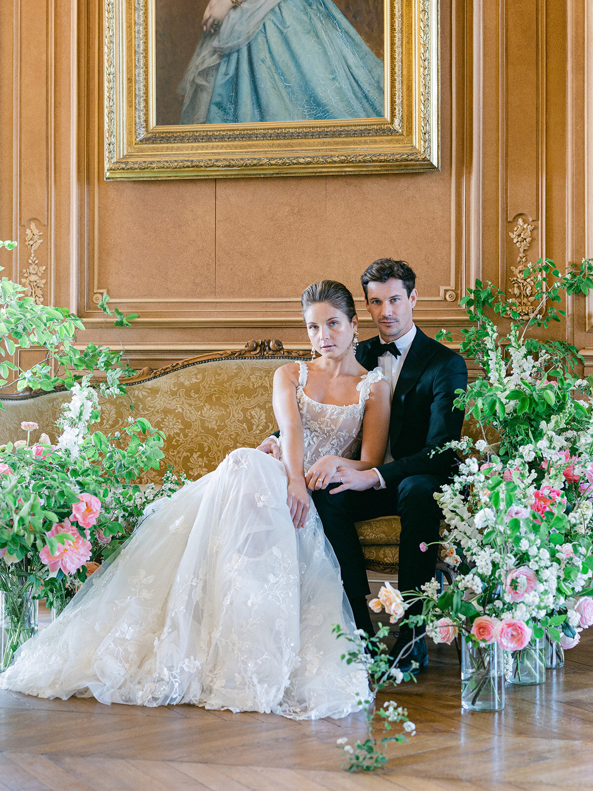 bride and groom on a sofa surrounded by flowers