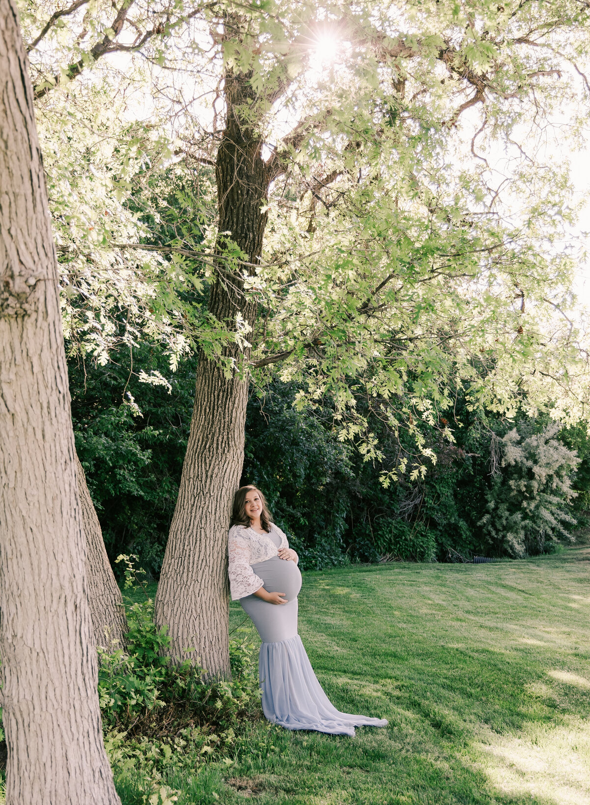 A young mother rests on a tree during her maternity shoot by Diane Owen Photography.