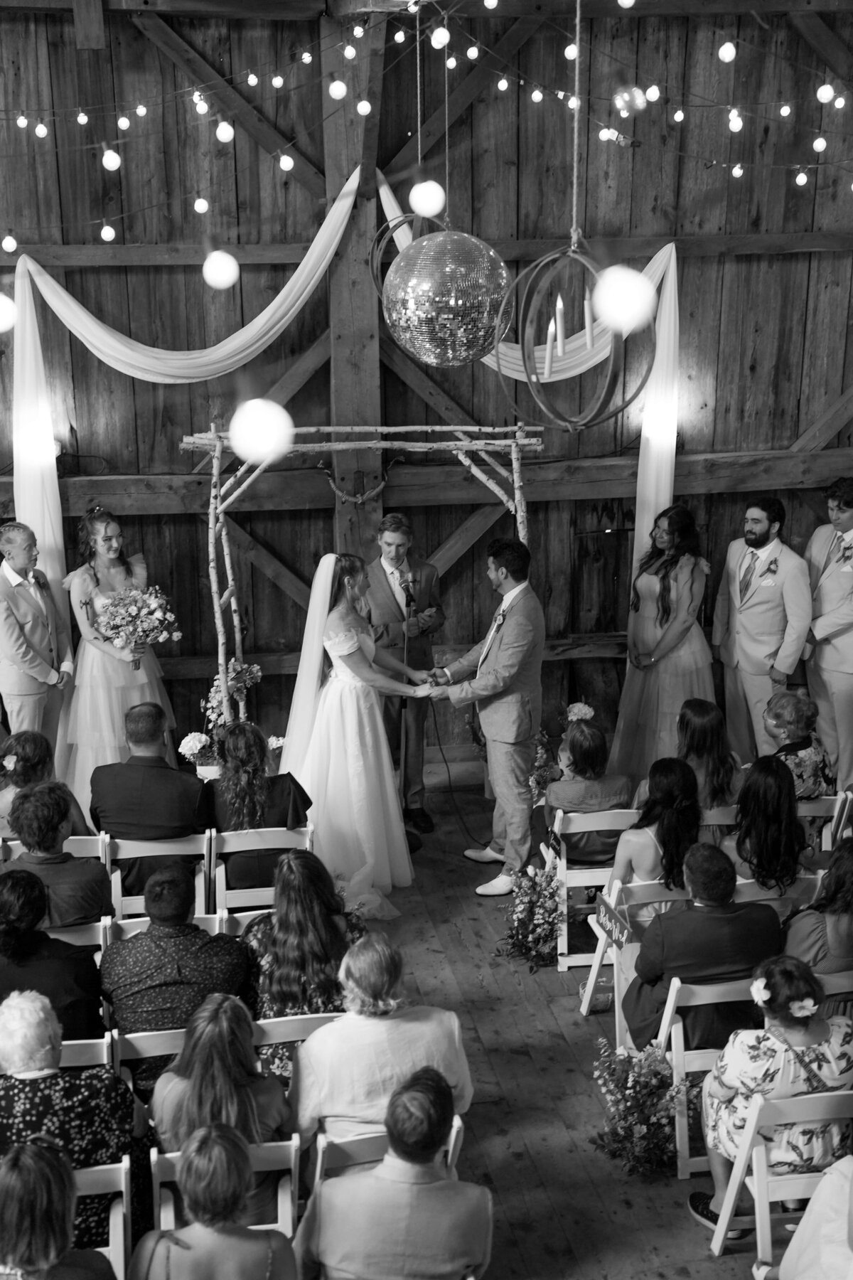 Bride and groom exchanging vows in a barn with decorative lights
